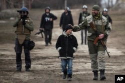 FILE - A Ukrainian serviceman speaks with a schoolboy in the village of Chermalyk, eastern Ukraine, Feb. 26, 2015.