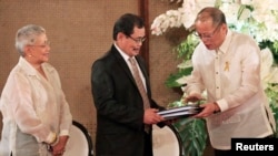Philippine President Benigno Aquino hands over the draft Bangsamoro Basic Law (BBL) to Moro Islamic Liberation Front (MILF) chief negotiator Mohagher Iqbal (C) ahead of the turnover ceremony of the law at the presidential palace in Manila, September 10, 2