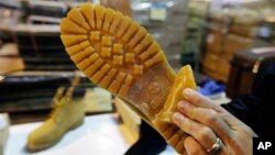 FILE - U.S. Customs and Border Protection Deputy Chief Officer Stephen Long shows how a Timberland brand on a counterfeit boot is hidden at a warehouse in Kearney, N.J., Oct. 28, 2015.