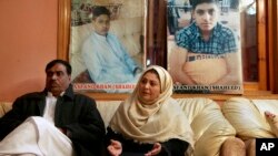 Pakistani mother Shahana with her husband Ajoon Khan sit next to photos of their son Asfand Khan, who was killed in a 2014 assault by Pakistani Taliban militants on an army public school, in Peshawar, Pakistan, Dec. 29, 2021.