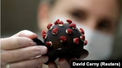A confectioner arranges a cake shaped like a microscopic view of the coronavirus SARS-CoV-2 at a bakery, Prague, Czech Republic.
