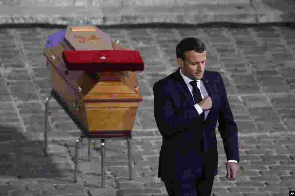 French President Emmanuel Macron leaves after paying his respects by the coffin of slain teacher Samuel Paty in the courtyard of the Sorbonne university during a national memorial event, Wednesday, Oct. 21, 2020 in Paris. French history teacher Samuel Pat
