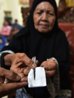 Seorang dukun bayi menunjukkan alat yang digunakan untuk sunat anak perempuan di Gorontalo, Provinsi Gorontalo, 20 Februari 2021. (Foto: Bay Ismoyo/AFP)