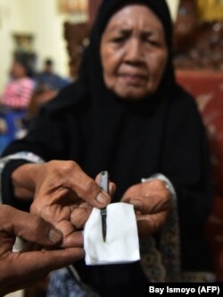 Seorang dukun bayi menunjukkan alat yang digunakan untuk sunat anak perempuan di Gorontalo, Provinsi Gorontalo, 20 Februari 2021. (Foto: Bay Ismoyo/AFP)