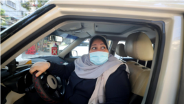 Palestinian woman Naela Abu Jibba, who started a women-only taxi service in the Gaza Strip, sits behind the wheel of her vehicle at Beach refugee camp in Gaza City on November 17, 2020. (REUTERS/Mohammed Salem)