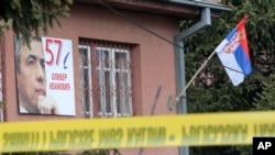 Polisi menyegel daerah di mana bendera Serbia dan gambar politisi Serbia Kosovo yang terbunuh Oliver Ivanovic terlihat di luar kantornya di bagian Mitrovica yang didominasi oleh Serbia, Kosovo, Selasa, 16 Januari 2018.