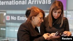 FILE - Negar Jourabchian looks at her mother Niloufar's passport after she traveled to the U.S. from Iran following a federal court's temporary stay of President Donald Trump's travel ban, at Logan Airport in Boston, February 6, 2017.