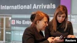 Une mère et sa fille regardent leurs passeport, à l'aéroport international de Boston, le 6 février 2017.