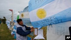 A man ties an Argentine flag carrying solidarity messages to a fence at the Mar de Plata Naval Base after the navy announced a sound detected during the search for the missing ARA San Juan submarine was consistent with that of an explosion, in Mar de Plata, Argentina, Nov. 23, 2017.