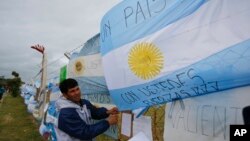 A man ties an Argentine flag carrying solidarity messages to a fence at the Mar de Plata Naval Base after the navy announced a sound detected during the search for the missing ARA San Juan submarine was consistent with that of an explosion, in Mar de Plat