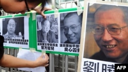 A protester affixes pictures of Chinese writer Mo Yan (L) and Chinese dissident Liu Xiaobo (R) to a gate during a demonstration in front of the Chinese liaison offices demanding the release of Chinese Liu in Hong Kong, October 13, 2012. 