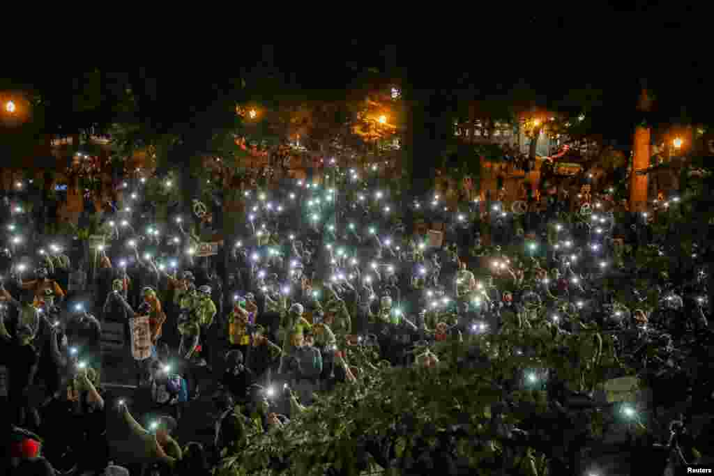 People turn cellphone flashlights on during a demonstration against racial inequality and police violence in Portland, Oregon, July 29, 2020.