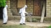 A healthcare worker in protective gear sprays disinfectant around the house of a person suspected to have Ebola virus in Port Loko Community, situated on the outskirts of Freetown, Sierra Leone, Oct. 21, 2014. 