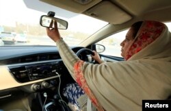 FILE - Yasmin Perveen, one of the pioneer women "captains" of Careem, adjusts her rearview mirror while driving her car in Islamabad, Pakistan, Dec. 7, 2016. In Saudi Arabia, only Saudi men will be allowed to drive Uber or Careem cars.