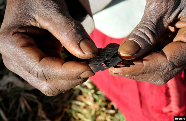 Prisca Korein, a 62-year-old traditional surgeon, holds razor blades before carrying out female genital mutilation on teenage girls from the Sebei tribe in Bukwa district, December 15, 2008.