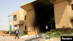 A man passes a bank building burnt during protests over cooking oil and fuel subsidy cuts in Khartoum, Sept. 26, 2013.