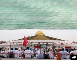 Buddhist monks and devotees sit outside the Wat Phra Dhammakaya temple in Pathum Thani province, north of Bangkok, Thailand, Thursday, June 16, 2016.