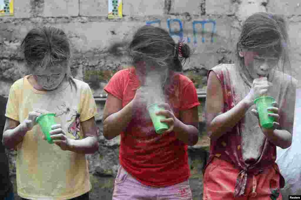 Girls&#39; faces are covered by white powder at a town fiesta parlour game, in celebration of patron saint Santa Rita de Cascia in Baclaran, Paranaque City, Metro Manila, Philippines.