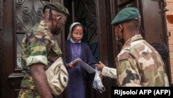 Des soldats de l'armée malgache distribuent des masques et des échantillons d'un remède traditionnel contre le coronavirus à la population à Antananarivo, à Madagascar, le 22 avril 2020. (Photo by RIJASOLO / AFP)