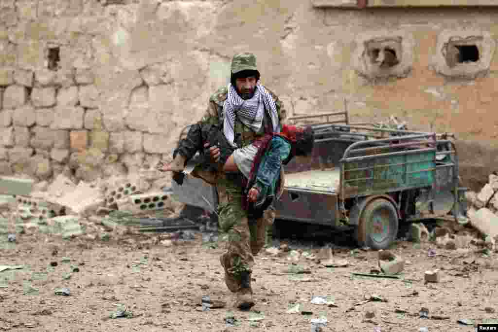 Combatente rebelde transporta criança ferida em Jub al Barazi&nbsp; e leste da cidade síria de al-Bab.