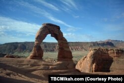 Mikah stands under Delicate Arch, an 18-meter-tall freestanding natural arch that is the most widely-recognized landmark in Arches National Park in southern Utah. It is depicted on the state's license plates.