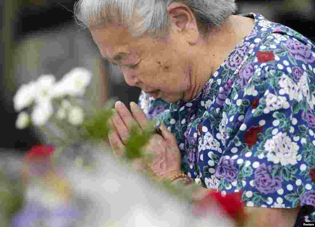 A woman prays for the victims of the 1945 atomic bombing, in the Peace Memorial Park in Hiroshima, in this photo taken by Kyodo, August 6, 2014.