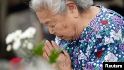 A woman prays for the victims of the 1945 atomic bombing, in the Peace Memorial Park in Hiroshima, in this photo taken by Kyodo, August 6, 2014.