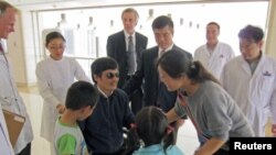 ນັກເຄື່ອນໄຫວຕາບອດຈີນ ທ່ານ Chen Guangcheng (ກາງ) ລົມກັນກັບພັນລະຍາຂອງທ່ານ ນາງ Yuan Weijing ແລະພວກລູກໆ ໃນຂະນະທີ່ເອກອັກຄະລັດຖະທູດສະຫະລັດ ປະຈຳປະເທດຈີນ ທ່ານ Gary Locke ລະຫວ່າງທ່ານ Chen ກັບເມຍ) ຢືນເບິ່ງ ຢູ່ໂຮງໝໍແຫ່ງນຶ່ງ ໃນນະຄອນຫຼວງປັກກິ່ງ (3 ພຶດສະພາ 2012)