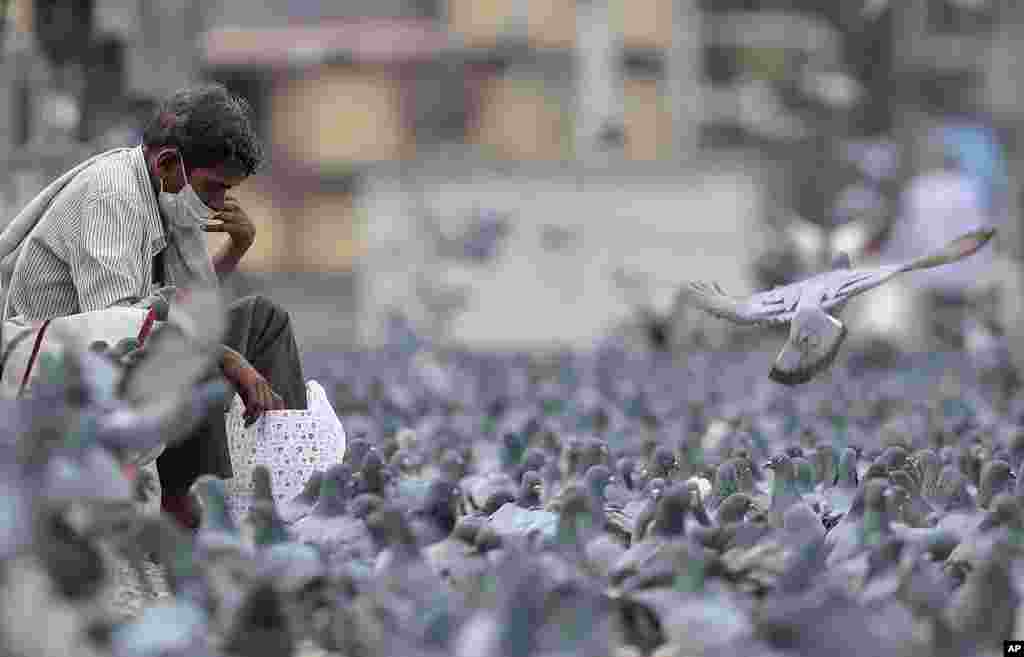 A man wearing a face mask is seen surrounded by pigeons during a lockdown aimed at preventing the spread of new coronavirus in Hyderabad, India.