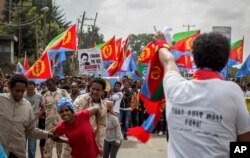 FILE - Eritrean exiles, some holding Eritrean flags and some dressed as Eritrean military members, simulating beatings and torture, left, rally outside the African Union headquarters, in Addis Ababa, Ethiopia, June 23, 2016.
