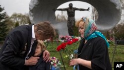 Alexander Burinin, ancien "liquidateur" de Tchernobyl, son épouse Olga et leur petit-fils Georgy visitant le cimetière de Mitino à Moscou, en Russie, le 26 avril 2016, lors du 30ème anniversaire de l'explosion de la centrale nucléaire de Tchernobyl. Environ 600.000 personnes, souvent appelées "les liquidateurs" de Tchernobyl, ont été envoyées pour combattre l'incendie à la centrale nucléaire après une explosion le 26 avril 1986.