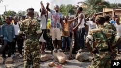 FILE - Oposition demonstrators confront army soldiers in the Mutarakura district, as security forces try to prevent people from moving out of their neighborhoods, in the capital Bujumbura, Burundi.