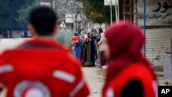 اعضای صلیب سرخ سوریه در نزدیکی کامیون حاوی کالاهای امدادی در شهر مضایا