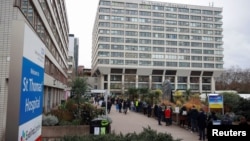 People queue outside a COVID-19 vaccination center at St. Thomas's Hospital in London, Dec.13, 2021. 