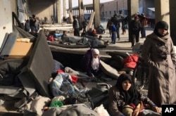 This image released by the International Committee for the Red Cross (ICRC) shows Syrians who were displaced with their families from eastern Aleppo gather at the collective shelter, in the village of Jibreen south of Aleppo, Syria, Dec. 12, 2016.