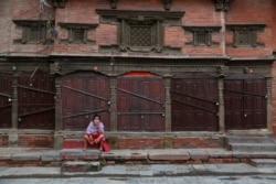 A Nepalese woman takes rest in front of a closed shop on her way back home from the market during lockdown in Kathmandu, Nepal, Tuesday, Aug. 25, 2020. Nepal is in second lockdown after COVID-19 cases continued to rise in various parts of the nation.