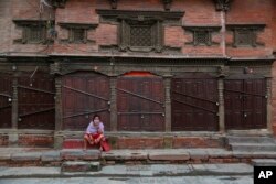 A Nepalese woman takes rest in front of a closed shop on her way back home from the market during lockdown in Kathmandu, Nepal, Tuesday, Aug. 25, 2020. Nepal is in second lockdown after COVID-19 cases continued to rise in various parts of the nation.