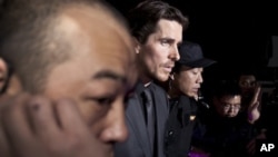 In this photo taken on Monday, Dec. 12, 2011, actor Christian Bale, center, is led by security guards upon arrival for an event of the Zhang Yimou-directed movie "The Flowers of War" in Beijing, China.