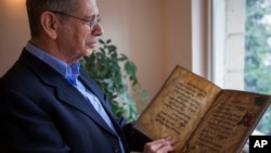 In this photo taken April 13, 2016, Eli Barzilai holds a copy of the Birds' Head Haggadah at his home in Jerusalem. 