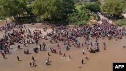 Vista aérea que muestra a los migrantes que llegan a México después de cruzar el río Suchiate desde Tecun Uman en Guatemala a Ciudad Hidalgo en México el 29 de octubre de 2018, un día después de que se reforzara una cerca de seguridad en el puente internacional para evitar que pasen.