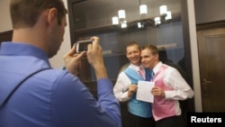 Mark Massey (C) and Dale Frost (R) pose for a picture after registering their marriage at the City Clerk's Office in New York, October 11, 2012.