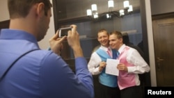 Anh Mark Massey (ở giữa) và anh Dale Frost (phải) cùng chụp ảnh sau khi đăng kí kết hôn tại New York, 11/10/2012. (REUTERS/Andrew Kelly)