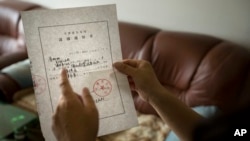 China Lawyers Crackdown: In this Wednesday, July 6, 2016 photo, Yuan Shanshan, the wife of detained Chinese lawyer Xie Yanyi, holds an official notice of Xie's detention from the Tianjin Public Security Bureau in their apartment in Miyun, on the outskirts of Beijing. 