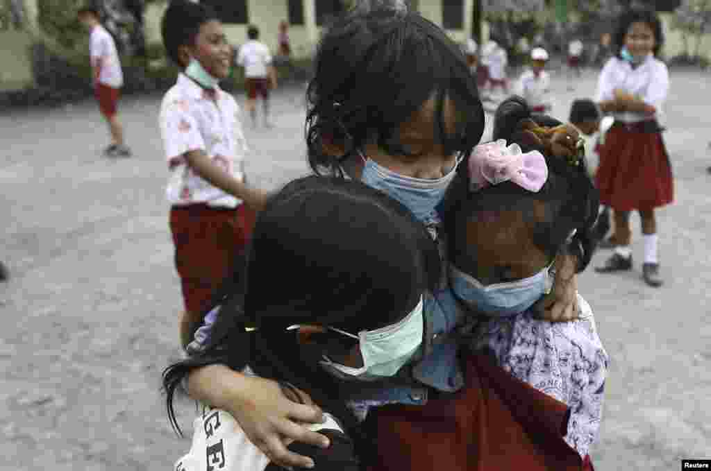 Murid-murid mengenakan masker wajah untuk melindungi diri dari abu vulkanik, di sekolah mereka di desa Tiga Ndreket di kabupaten Karo, Sumatera Utara (6/11). (Reuters/Y.T. Hartono)