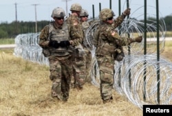 U.S. Army soldiers from Ft. Riley, Kansas, put up barbed wire fence for an encampment to be used by the military near the U.S.-Mexico border in Donna, Texas, Nov. 4, 2018.