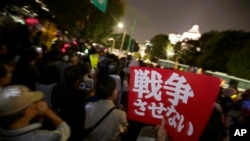 A sign that reads: "We won't let Japan go to war" is held by a protester as people gather for an anti-war rally in front of the National Diet building in Tokyo, Tuesday, Sept. 15, 2015.