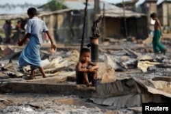 FILE - A boy sits in a burned area after fire destroyed shelters at a camp for internally displaced Rohingya Muslims in western Rakhine State near Sittwe, Myanmar, May 3, 2016.