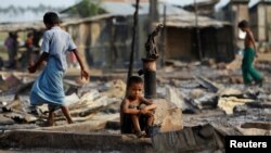 FILE - A boy sits in a burned area after fire destroyed shelters at a camp for internally displaced Rohingya Muslims in western Rakhine State near Sittwe, Myanmar, May 3, 2016.