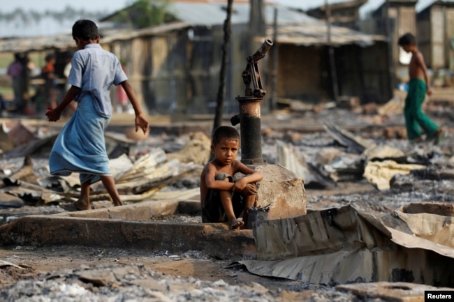 FILE - A boy sits in a burned area after fire destroyed shelters at a camp for internally displaced Rohingya Muslims in western Rakhine State near Sittwe, Myanmar, May 3, 2016.