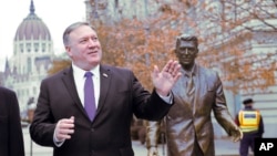 Menlu Amerika Mike Pompeo berpose di dekat patung Presiden Ronald Reagan di Budapest, Hongaria, Senin (11/2). 